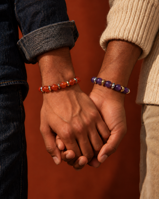 Two hands holding, wearing a carnelian bracelet and an amethyst bracelet by LINDA&LILO